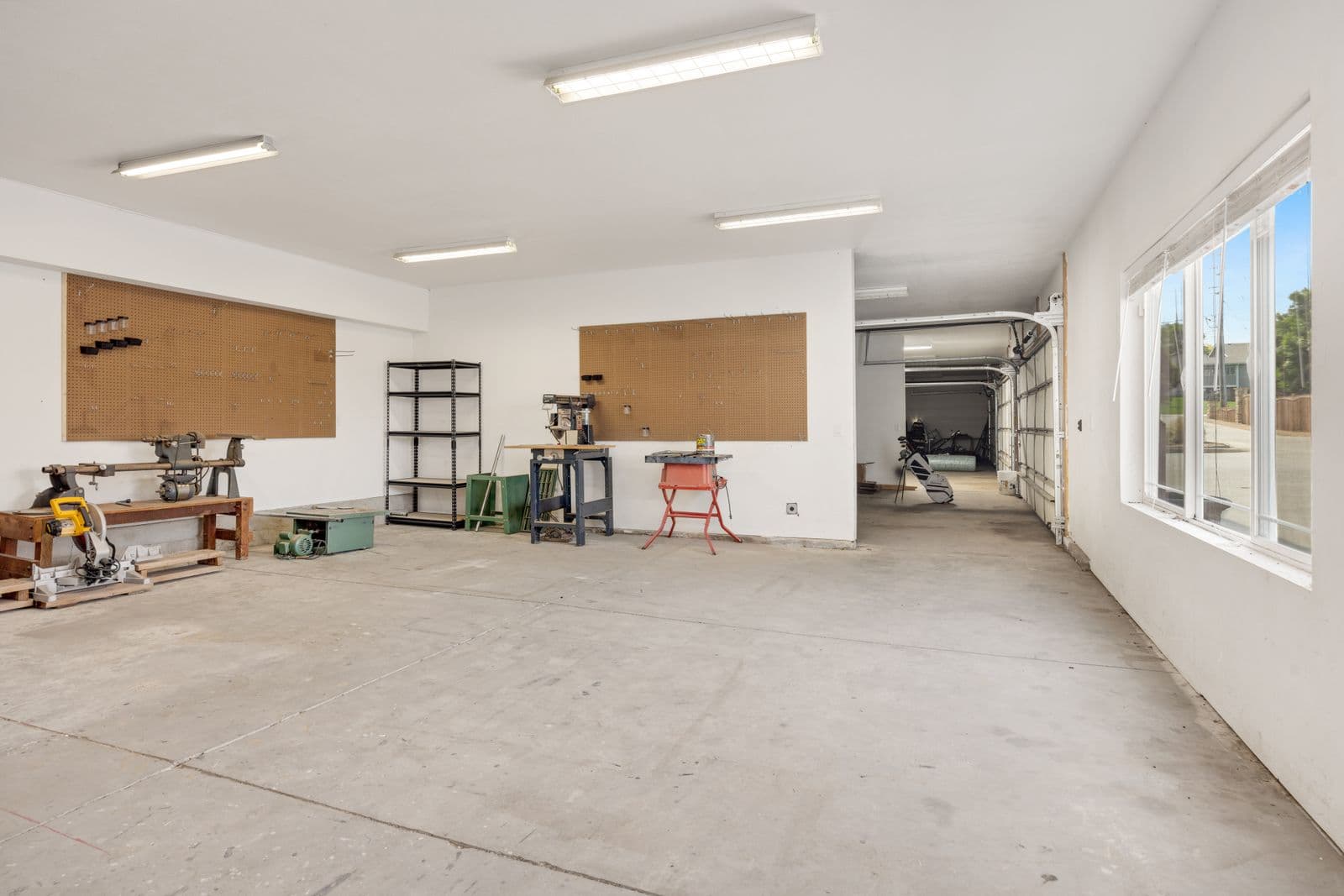 Clean bare concrete floor in a bright workshop garage — sound concrete after removal, ready to rebuild on